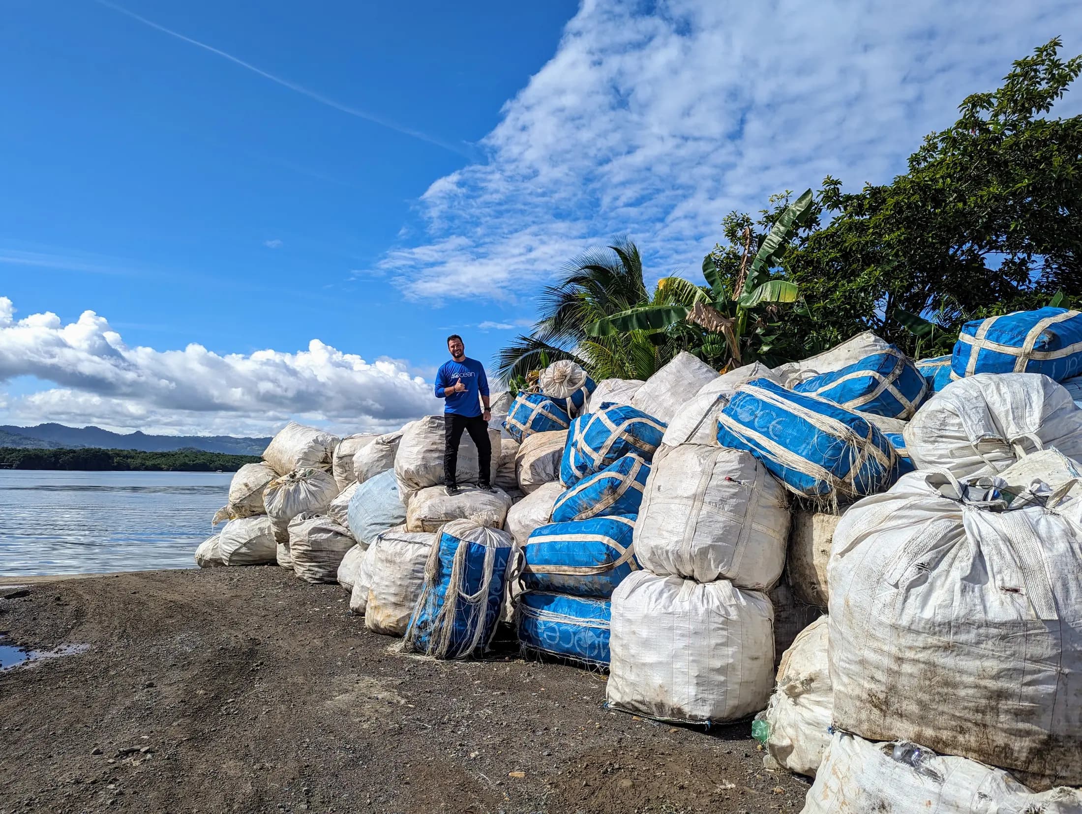 Grant Kendzior standing on a stack of bagged plastic recovered from a coastline