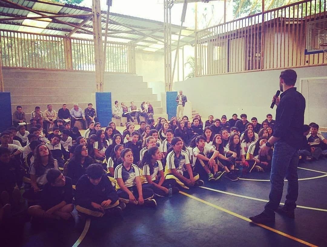 Grant Kendzior addressing a school assembly of students seated on a gymnasium floor